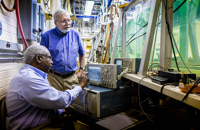 Two scientists working with computer charts and an aqua tank