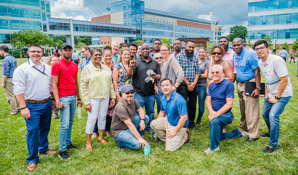 A group of people pose for a photo on Johns Hopkins APL's Central Green