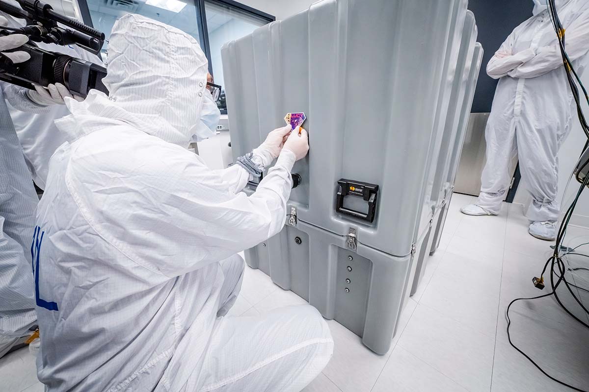 A member of the Lucy LORRI team places a sticker of the logo for NASA’s Lucy mission on the shipment container