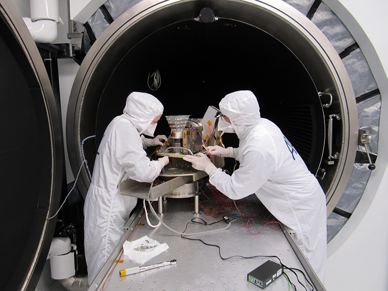 Katherine Rorschach and Mark Hoff set up the engineering model of the Europa Imaging System’s Wide Angle Camera in an APL thermal-vacuum chamber for environmental testing
