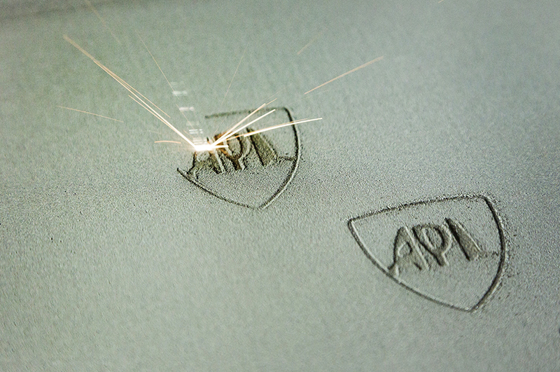 This image illustrates the selective laser melting of the powder bed in an APL logo.