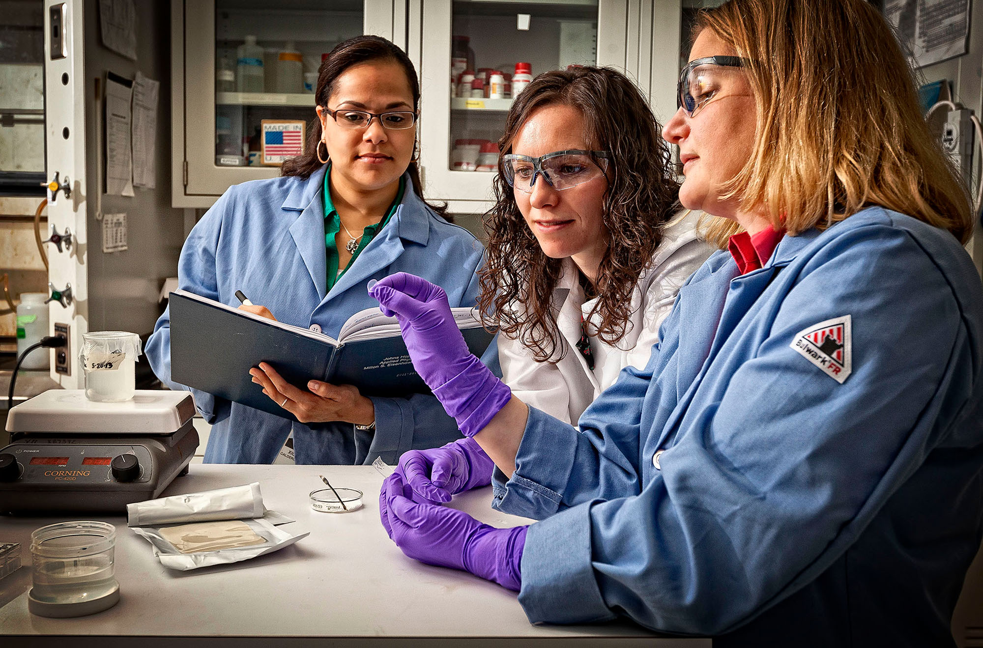 Three APL staff members work in a lab