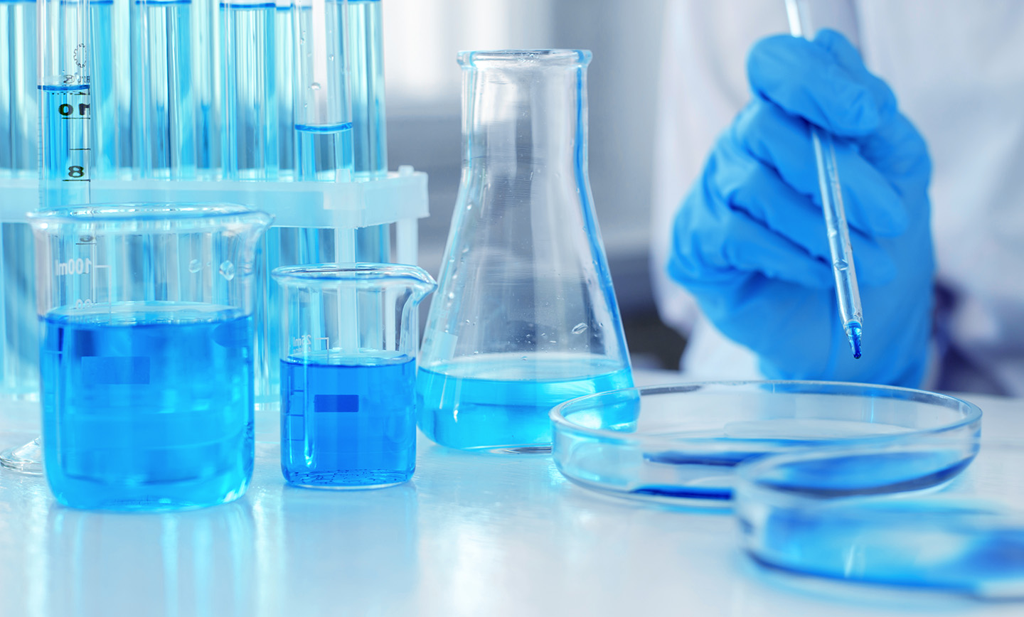 A scientist uses a pipette to drop a sample into a petri dish