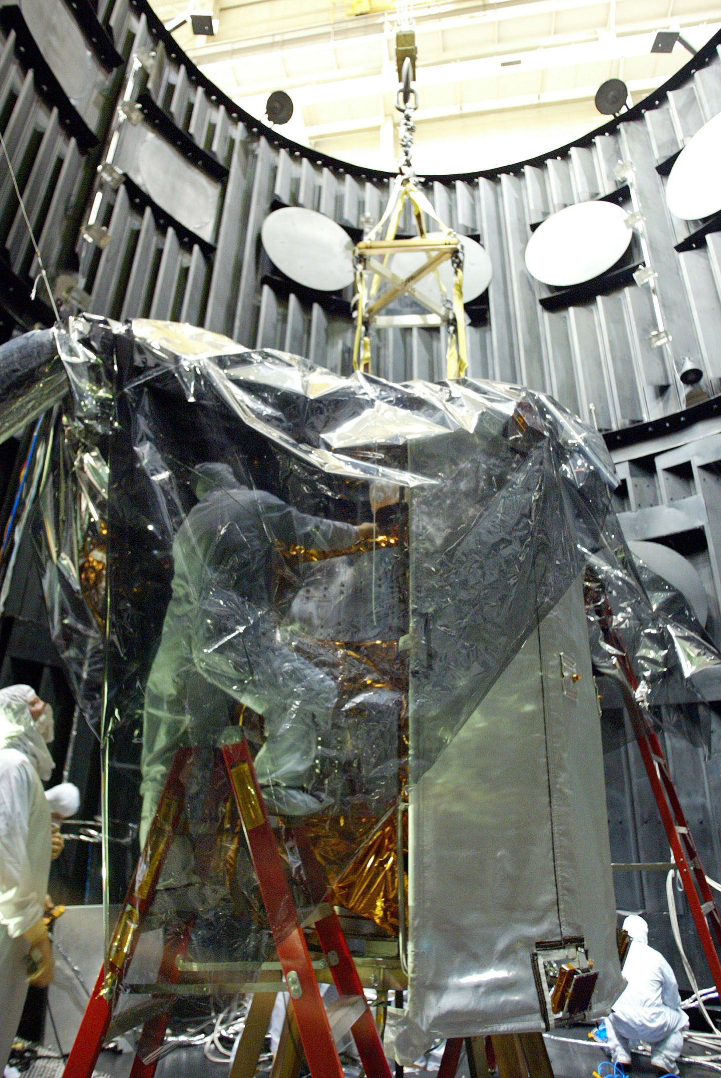 Engineers wrap the MESSENGER spacecraft in protective film before lifting it out of the thermal-vacuum chamber 