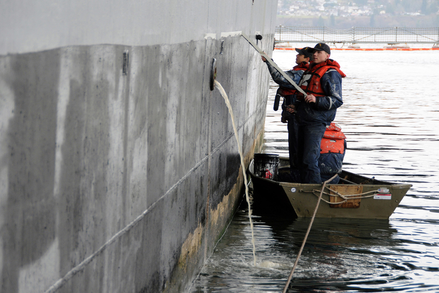 Sailors from the deck department of the aircraft carrier USS Abraham Lincoln mask and paint the ship’s hull below the waterline.