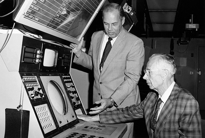At the radar display, Director Alexander Kossiakoff (seated) and James Austin view combat information from SYS-1