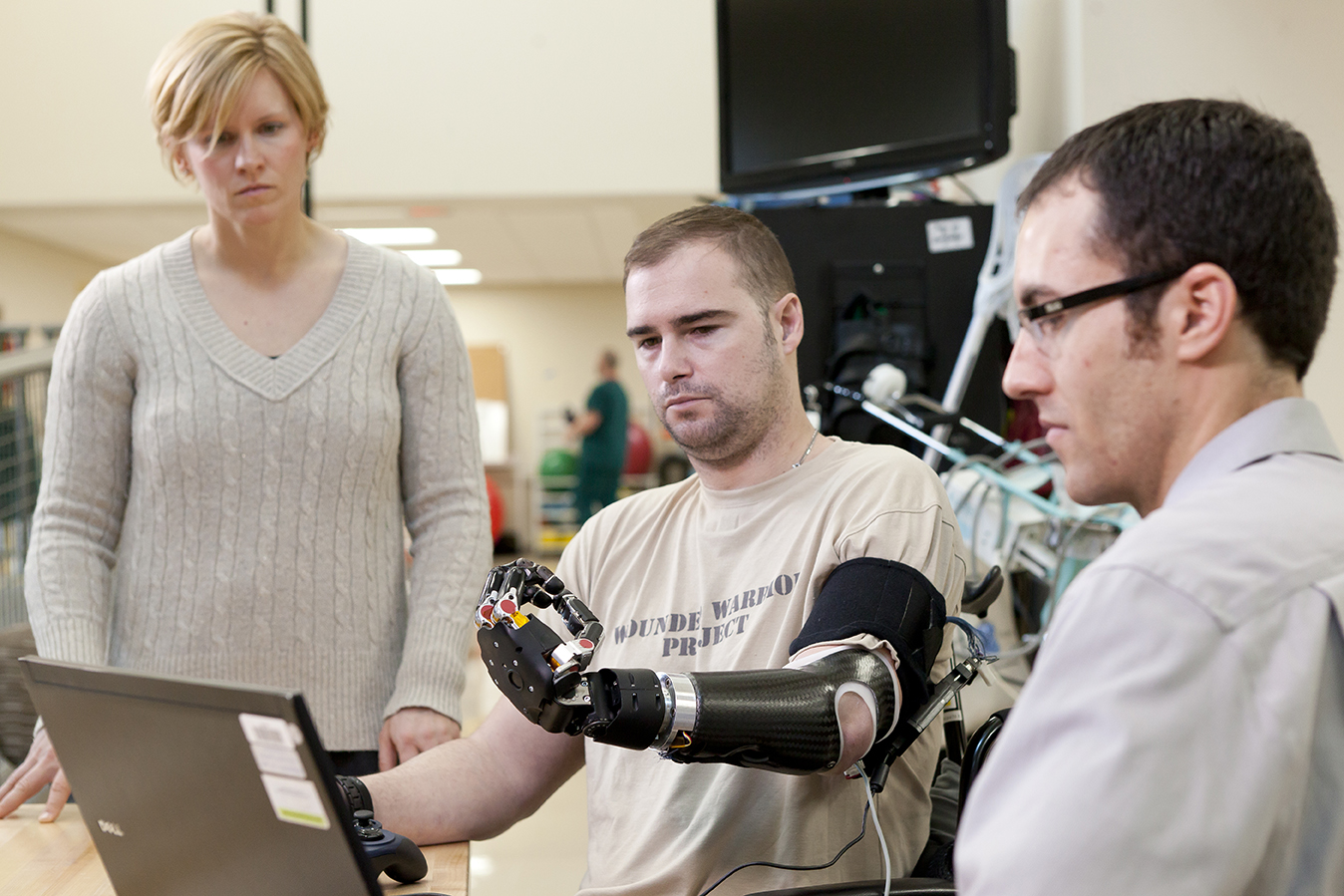 APL engineers Courtney Moran (left) and Bobby Armiger (far right) work with Technical Sergeant Joe Delauriers as he controls the Modular Prosthetic Limb (MPL) at Walter Reed National Medical Center.