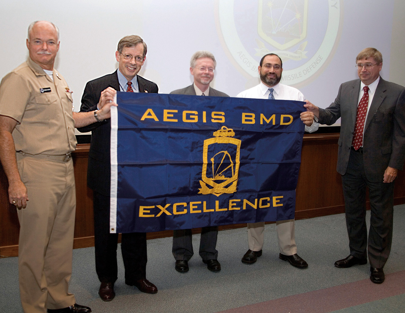 Aegis Ballistic Missile Defense Program Director Rear Adm. Alan Hicks (far left) and Executive Director Larry Rogers (far right) present the flag to APL Director Rich Roca, APL Aegis BMD Program Manager Joel Miller, and Test and Evaluation Project Manager Joe Mulé 