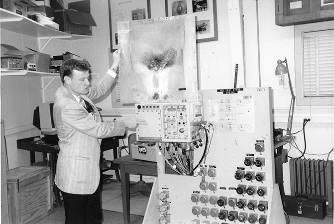 Systems engineer Bruce Land holds a scorched submarine shipboard panel that has been damaged by arc faults (short circuits) in the main power switchboard.