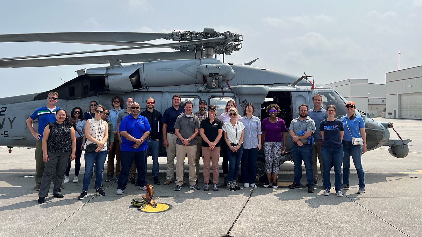 APL tour participants pose in front of a U.S. Navy MH-60S helicopter