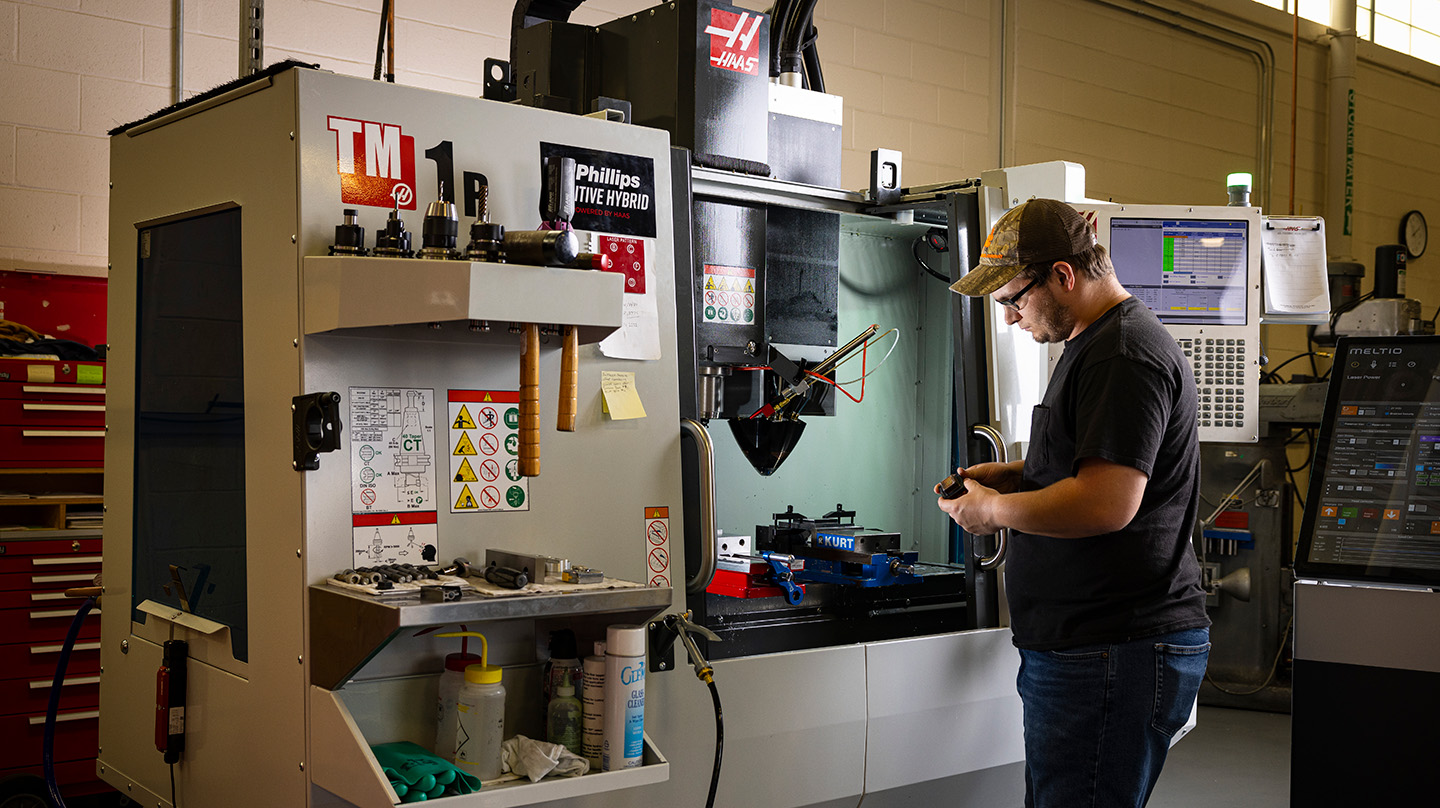 A senior mechanical fabrication technician at Johns Hopkins APL adjusts parts on a 3D printer.