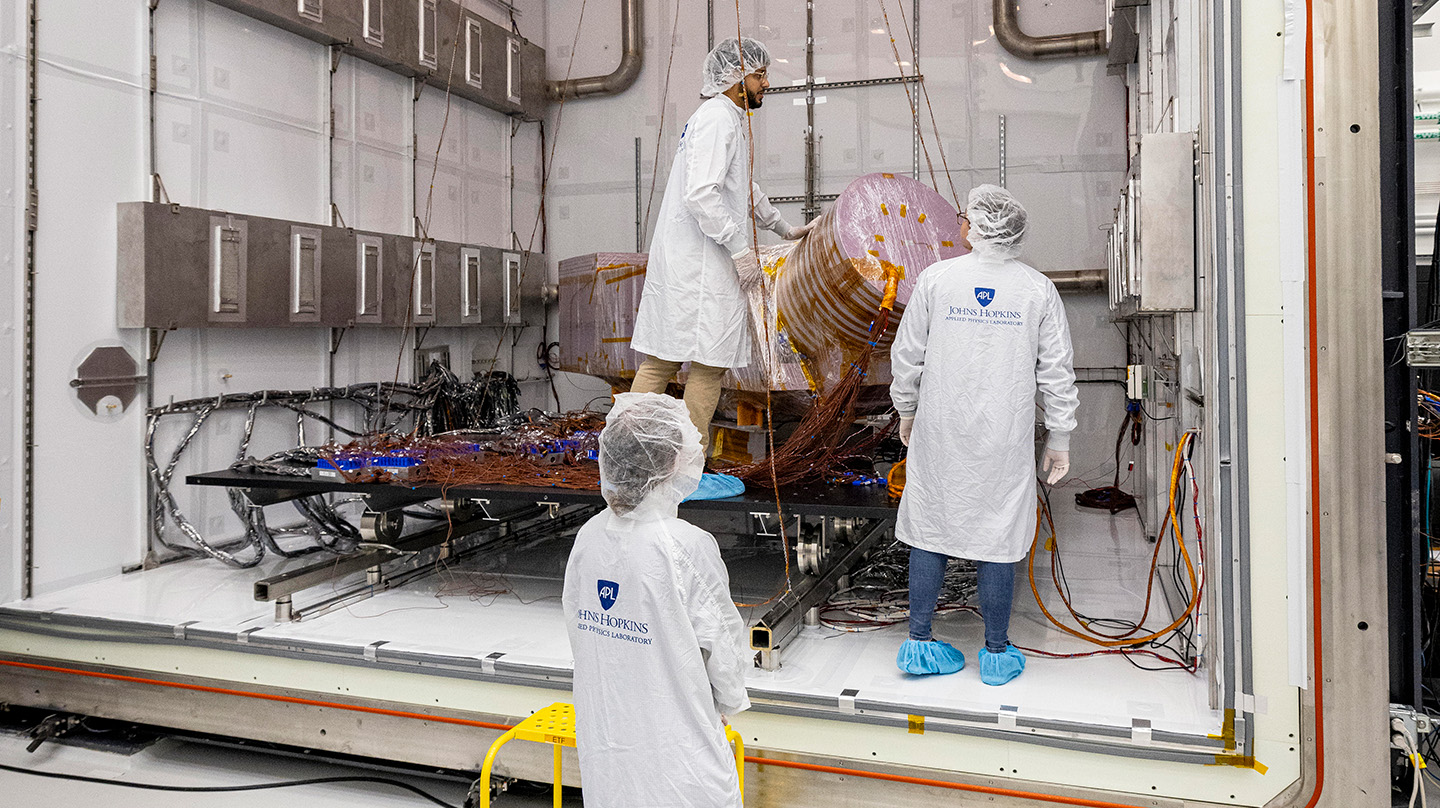 Dragonfly team members Diarny Fernandes, Ashley Lakey, Rachel Fox ready the Dragonfly thermal development test module (DTM) for temperature and atmospheric condition tests in the APL’s Titan Chamber.