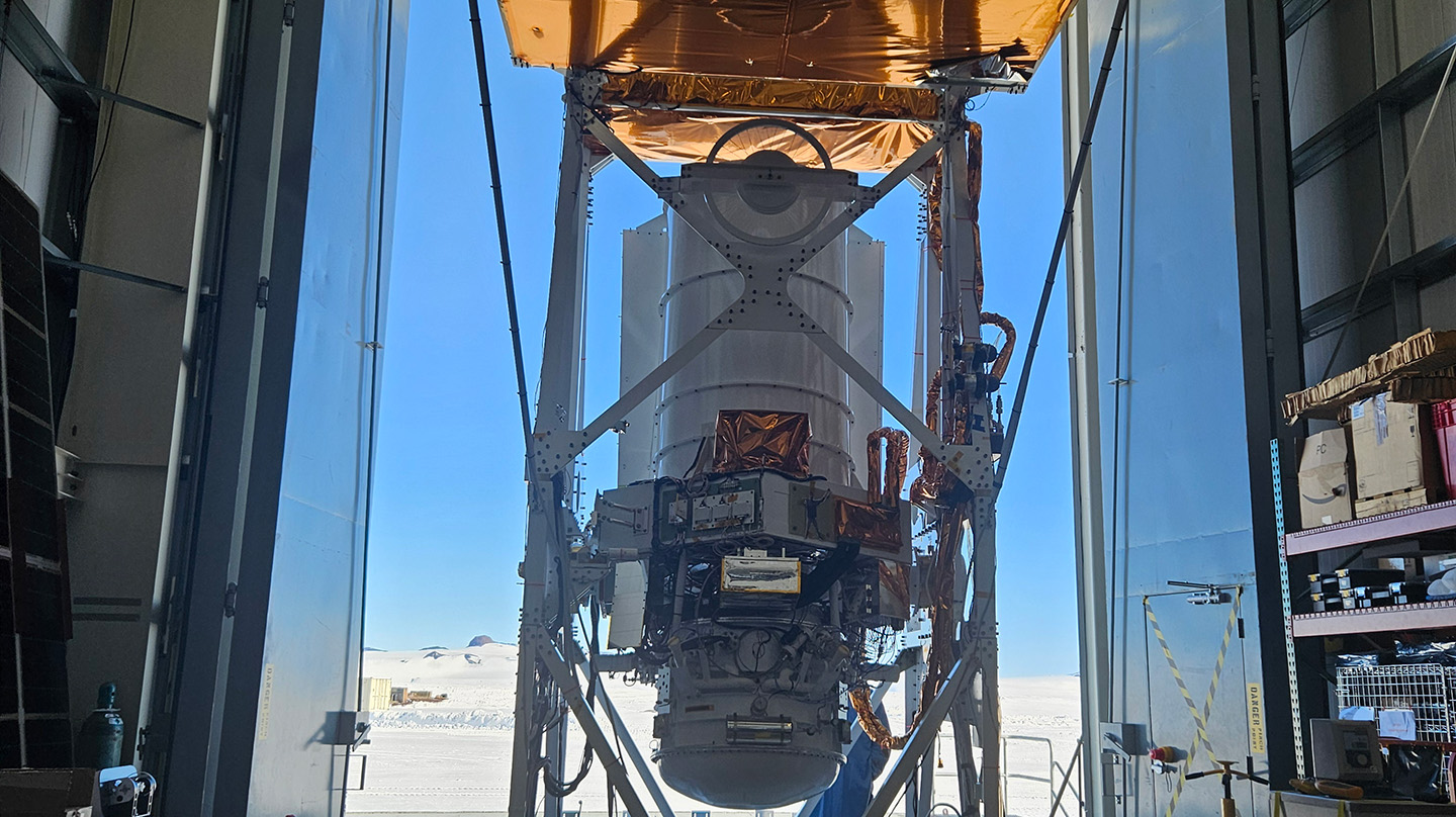 The GUSTO telescope hangs from the hangar crane