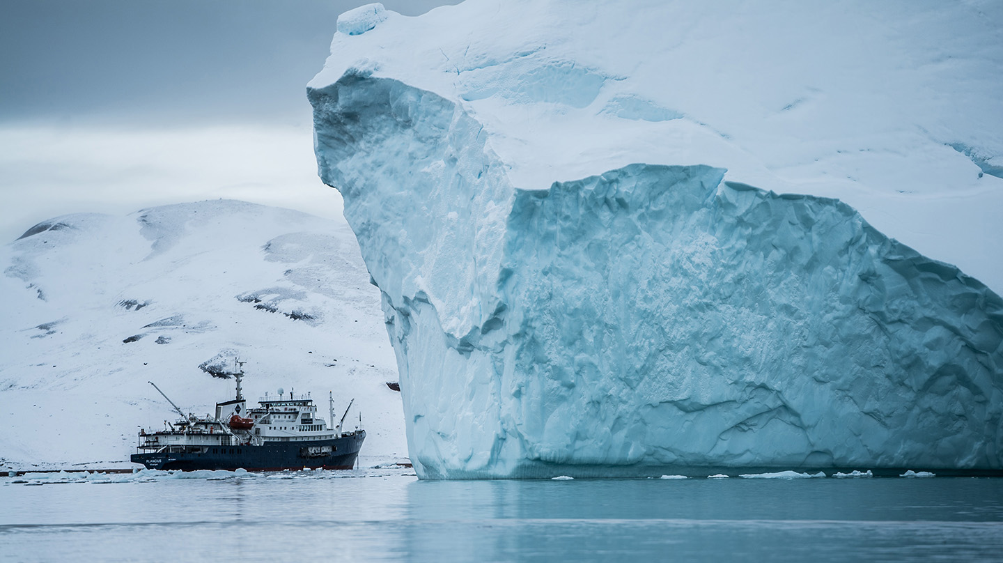 A vessel passes by icebergs near Greenland (Credit: Hubert Neufeld)