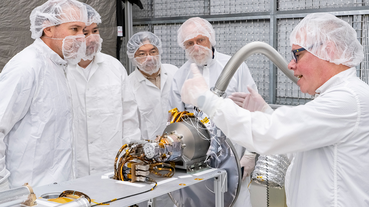 U.S. and Japanese team members gather around and discuss the gamma-ray spectrometer portion of the MEGANE instrument during its development at Johns Hopkins APL