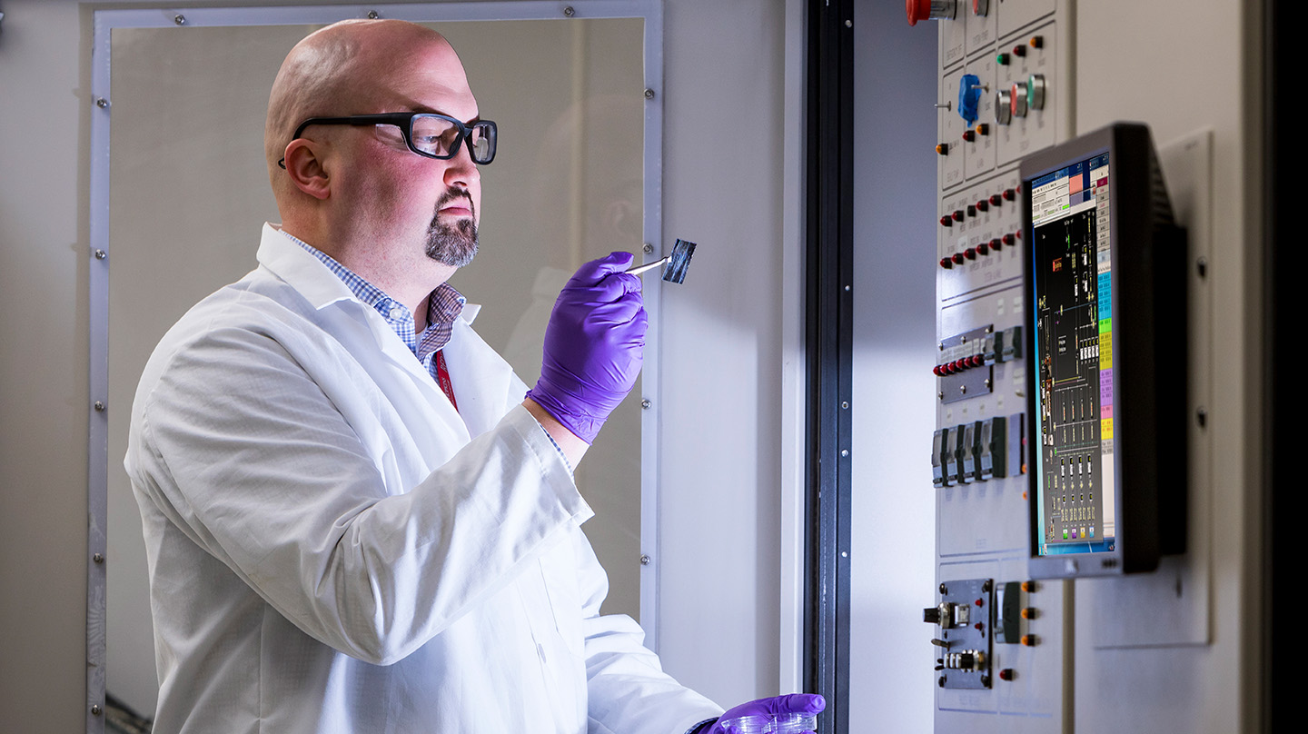 Jon Pierce, a senior research engineer at APL, examines a thin film grown using metal-organic chemical vapor deposition