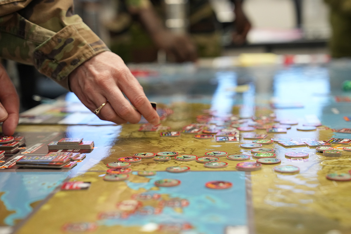 Students move pieces around the board during a war-game based on Pacific conflict while attending Air War College at Maxwell Air Force Base, Alabama, December 21, 2023. Game phases are actioned with a deck of cards, spawning new and viable assets with each play. These items can range from instituting an element of air superiority to launching an information campaign. (U.S. Air Force photo by Billy Blankenship) (VIRIN: 231221-F-VZ654-1004)