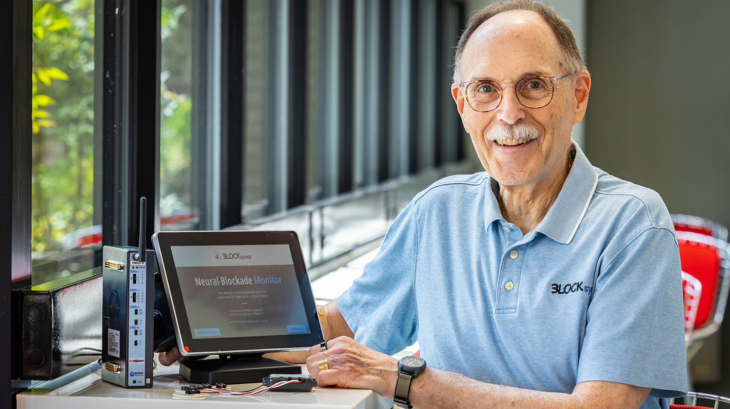 Wayne Sternberger, former APL staff member and recipient of the Laboratory’s first Archimedes Award, sits beside his invention — the neural blockade monitor. (Credit: Johns Hopkins APL/Ed Whitman)