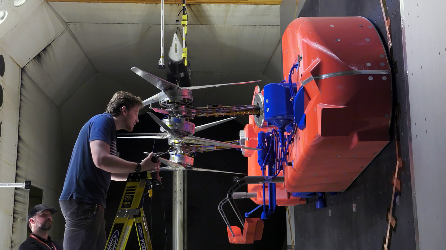 Technicians install and adjust the rotors on the full-scale test model representing half of the Dragonfly lander in the Transonic Dynamics Tunnel facility at NASA’s Langley Research Center.