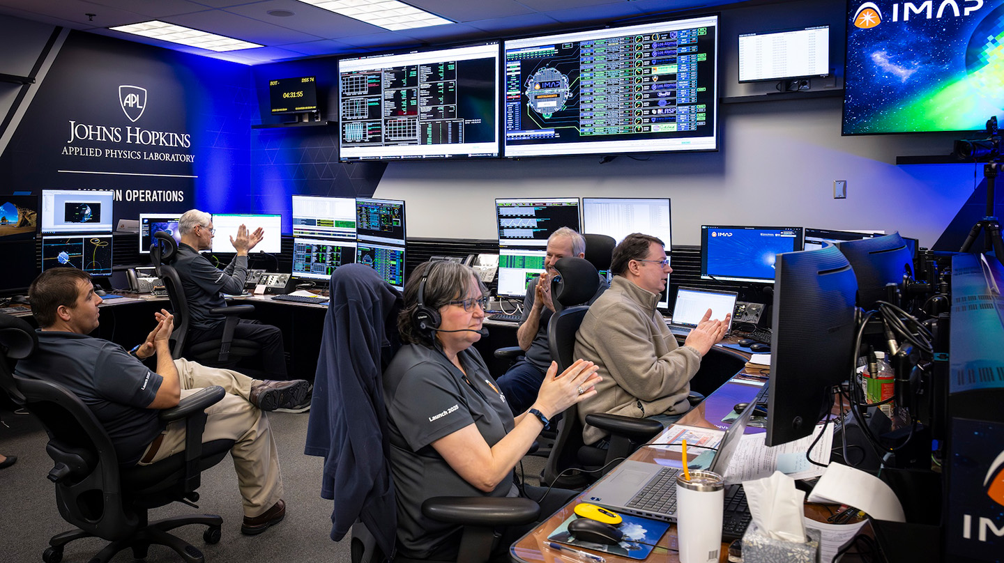 Flight controllers and spacecraft team members in the Mission Operations Center at Johns Hopkins APL celebrate as IMAP completes the last of the maneuvers to position itself in orbit around the first Sun-Earth Lagrange point