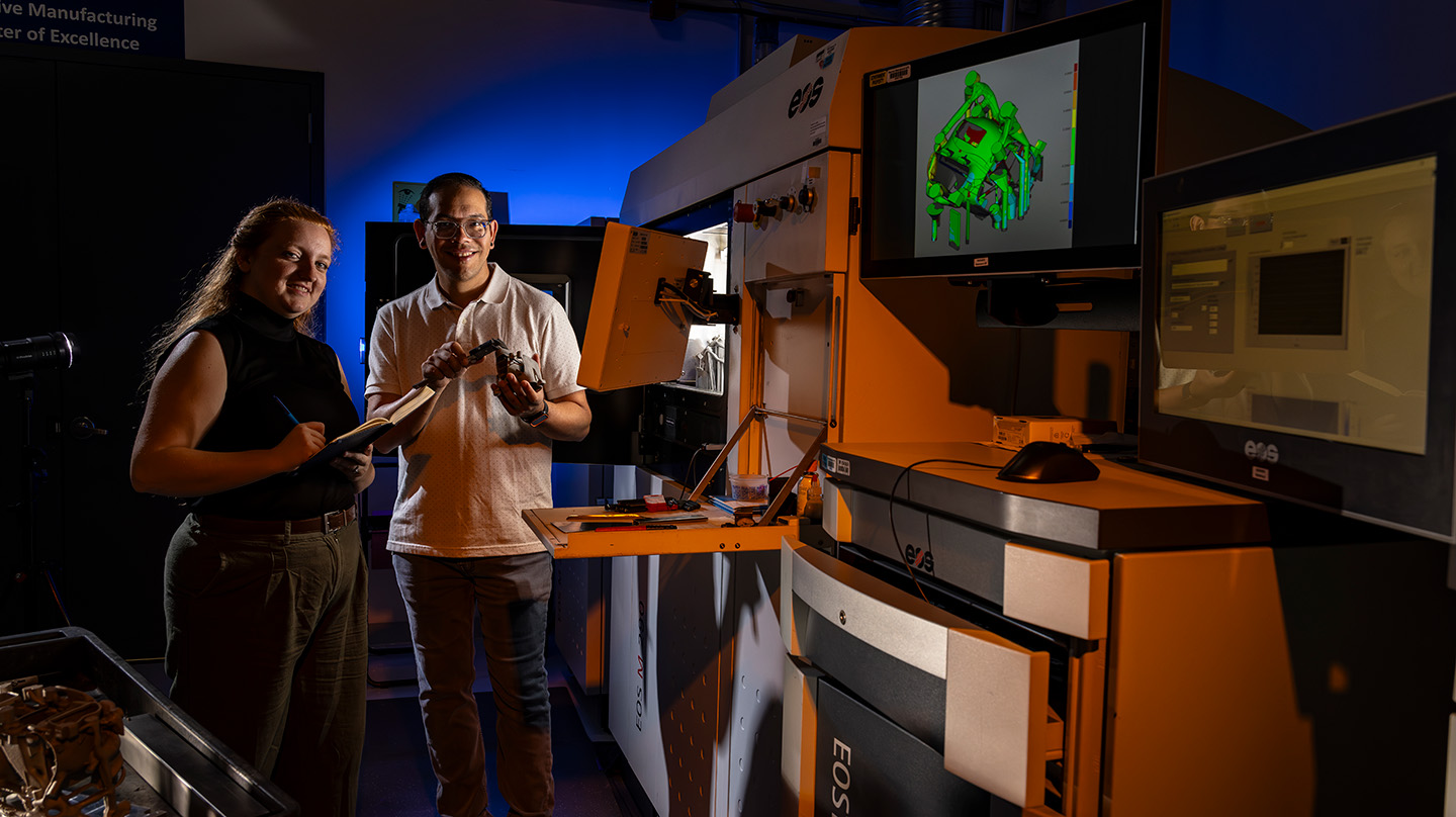 Mary Daffron and Sam Gonzalez inspect a part after fabrication on the EOS M 290 metal 3D printer