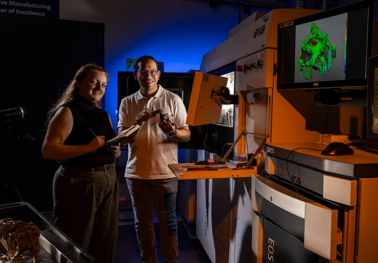 Mary Daffron and Sam Gonzalez inspect a part after fabrication on the EOS M 290 metal 3D printer, augmented with advanced control and sensing tools, in the APL Advanced Manufacturing Lab.