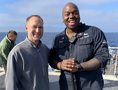 Allen shares a laugh with Petty Officer 2nd Class Ahmed Dunn after giving him an AMDS coin for his exceptional attitude and for escorting his group during his tour onboard the USS Princeton (CG-59).