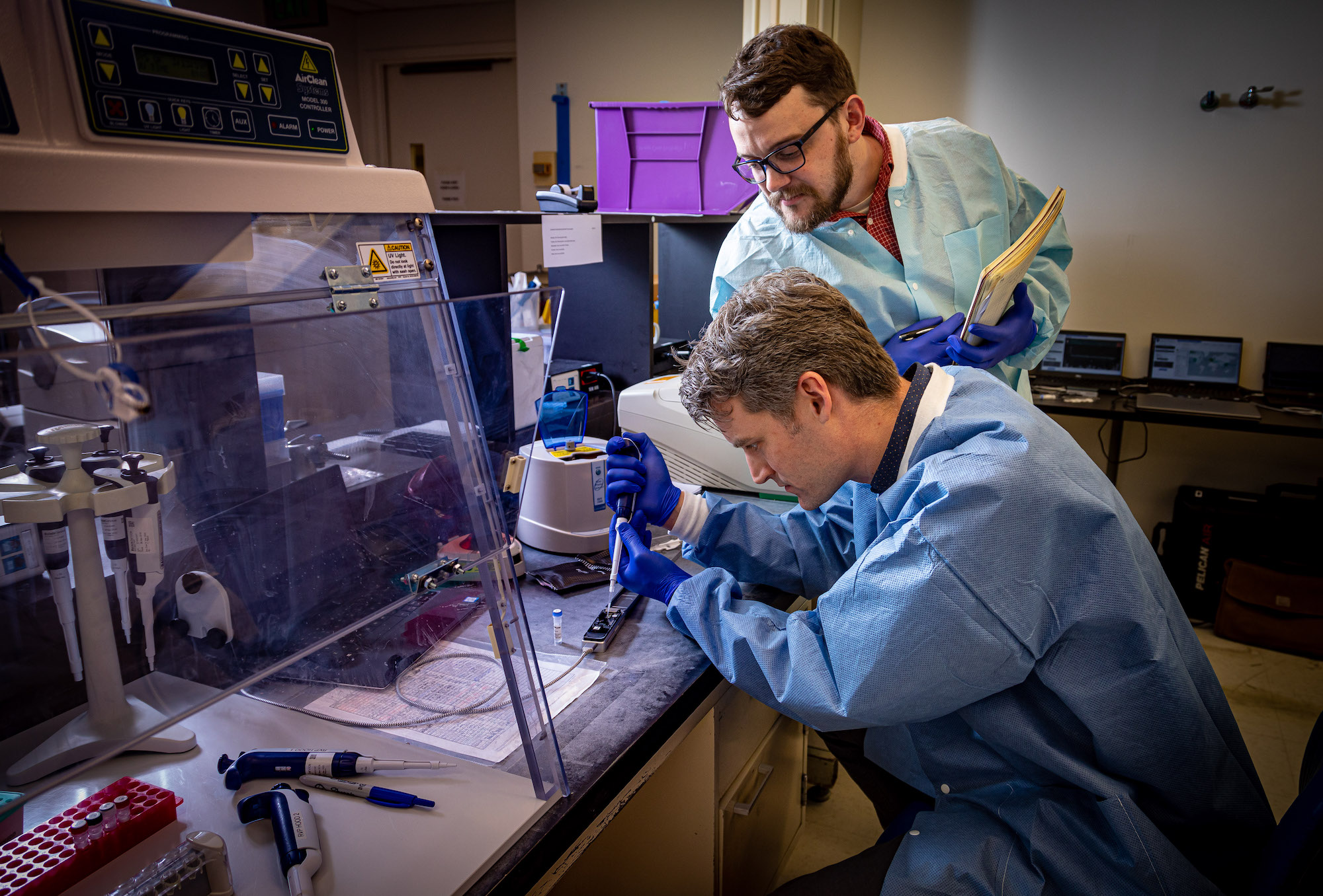 Peter Thielen, front, and Tom Mehoke, biologists from Johns Hopkins Applied Physics Laboratory prepare a hand-held DNA sequencer for operation at the molecular diagnostics laboratory at Johns Hopkins Hospital.