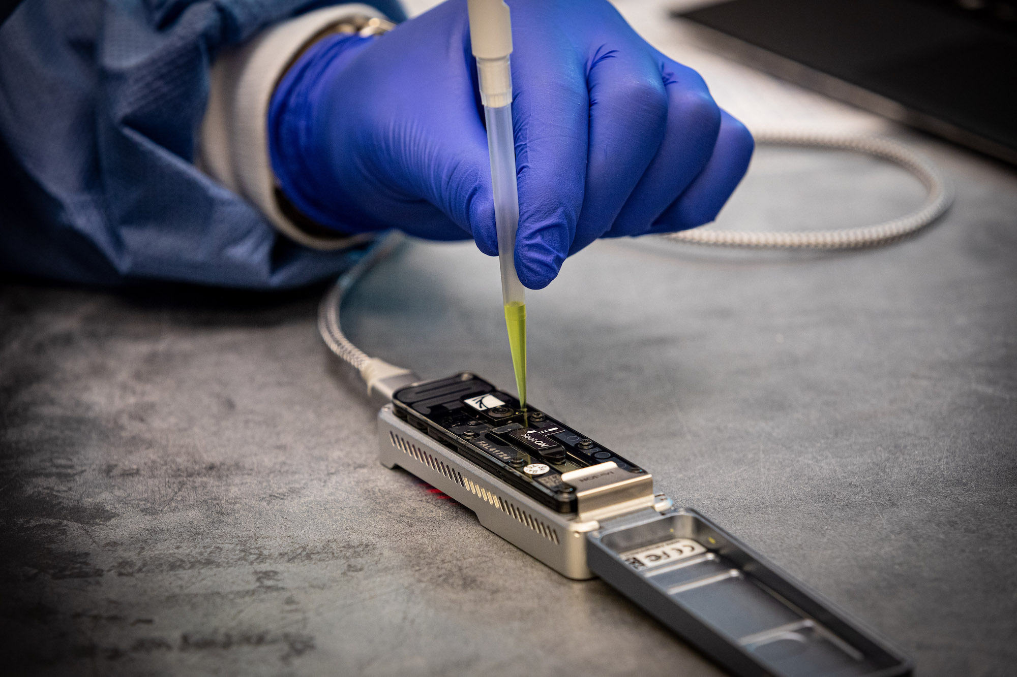 A loading buffer is injected into a hand-held DNA sequencer to prepare it for operation.