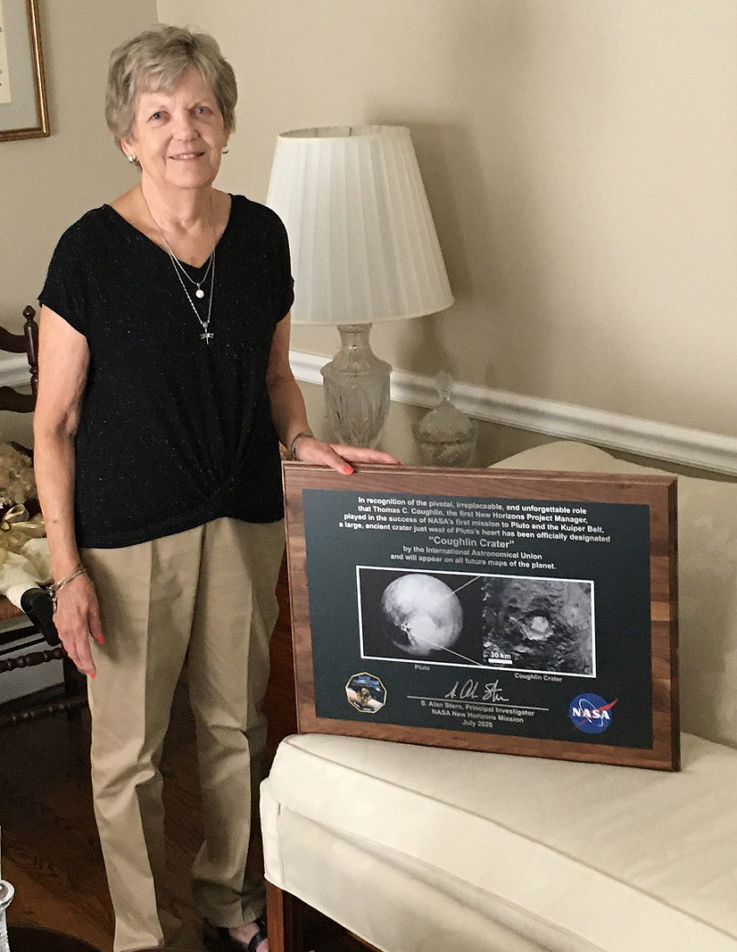 Joan Coughlin with the plaque presented to her by the New Horizons team, showing the location of Pluto’s 20-mile-wide Coughlin crater. The feature, located near Pluto’s famous heart-shaped glacier, is named in honor of Tom Coughlin, Joan’s husband of 51 years and New Horizons’ first project manager.  Credit: Glen Fountain