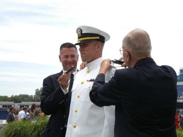 Brooks, center, gets his officer shoulder boards pinned by his father, left, and grandfather at the Naval Academy’s commissioning day in 2009.  Credit: Owen Brooks