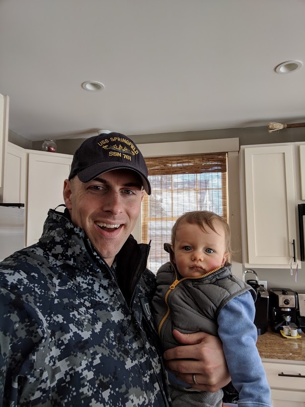 Brooks holds his son, Jacob, before leaving for work at the Portsmouth Naval Shipyard in 2018.  Credit: Owen Brooks