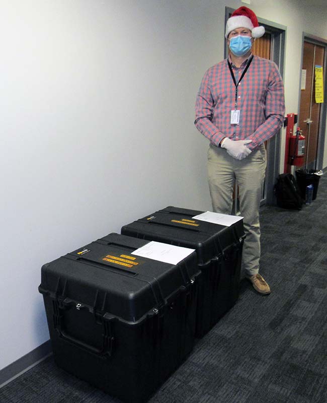 Spencer Disque, the engineering lead on the MEGANE structural thermal model at APL, stands with the two shipping containers that house the MEGANE structural thermal model components.