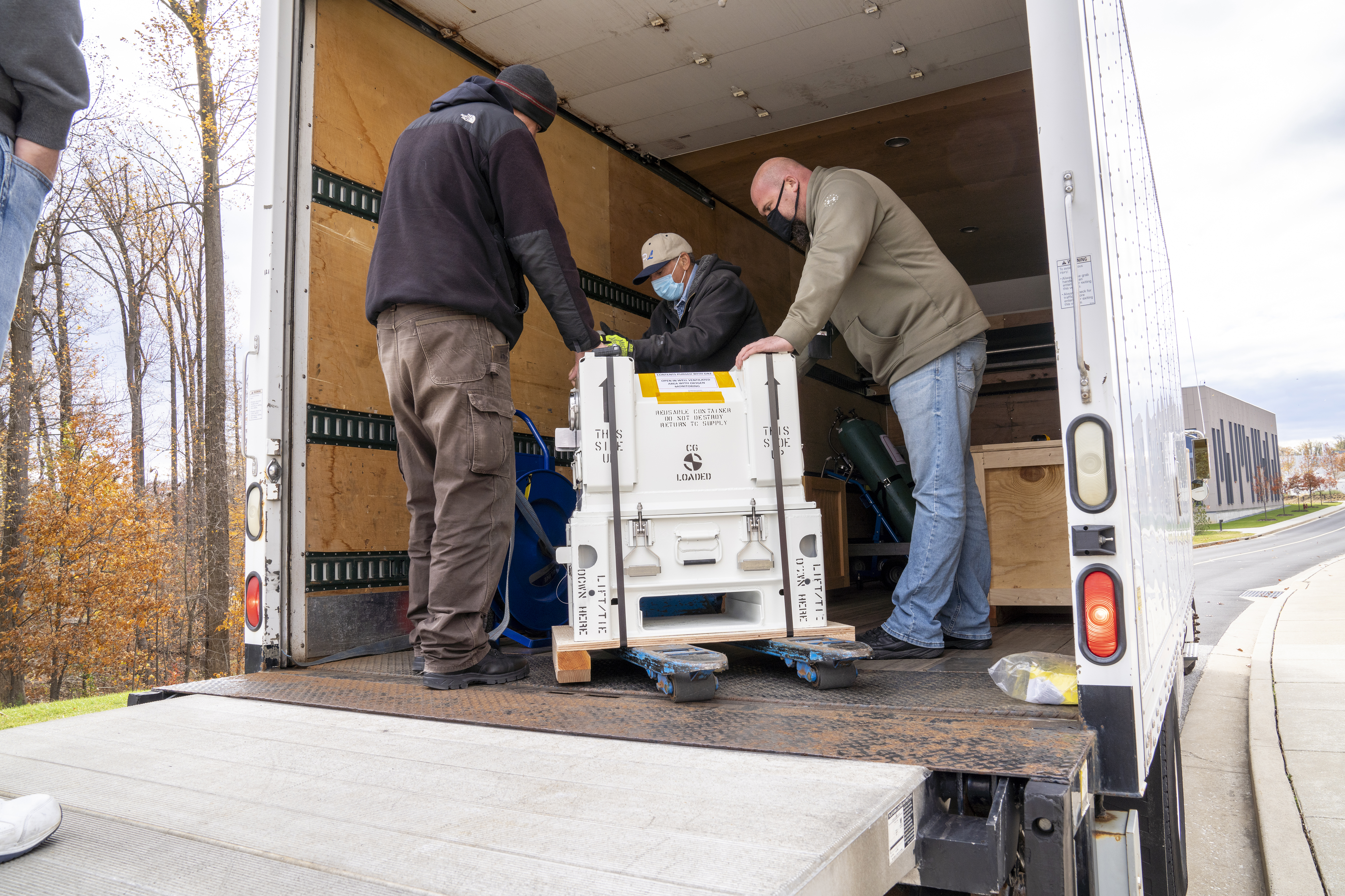 MISE team members place the container in a shipping truck