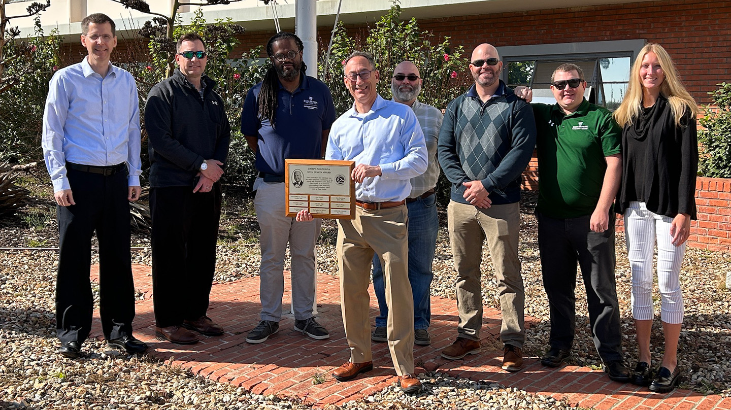 At the 2023 Military Sensing Symposia, National Security Sensor and Data Fusion conference, Newman (holding plaque) was joined by APL team members (from left) Stephen Vance, Frank Bantell, Zerotti Woods, Jim Farrell, Chris Palumbo, Jason Miller and Alexis Bensen.